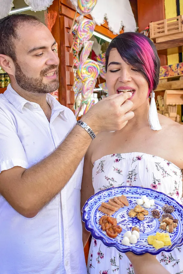 Pareja de viajeros probando dulces tradicionales mexicanos servidos en un plato de talavera.